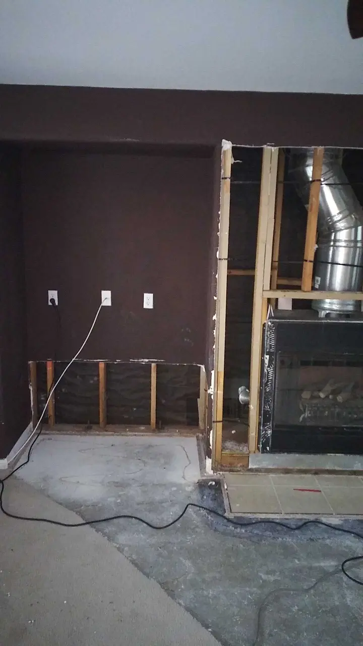 Opened fireplace wall and flooring during mitigation during Beaumont water damage restoration project by PL Builders