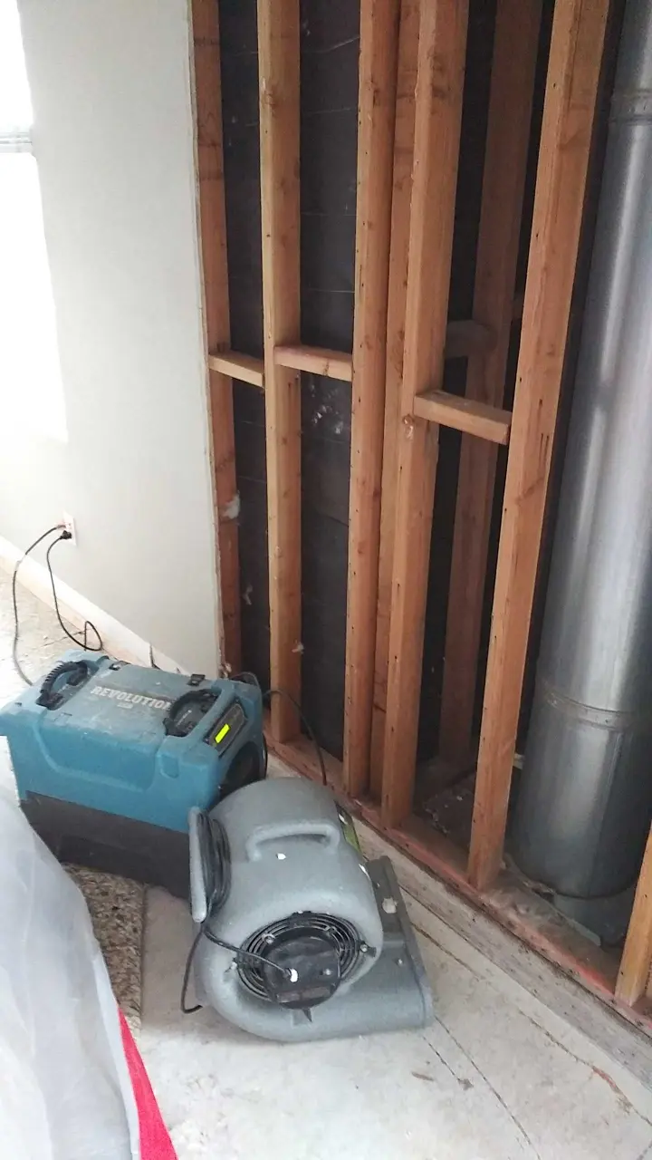 Opened wall cavity with drying equipment during Beaumont water damage restoration project by PL Builders