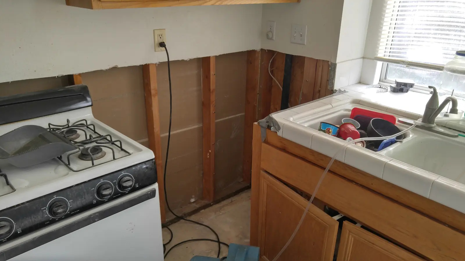 Kitchen cabinet area opened after burst pipe: Jurupa Valley water damage restoration project by PL Builders showing burst pipe kitchen water damage repair