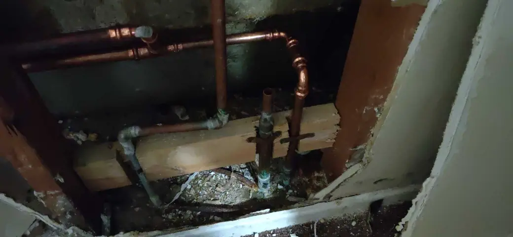 Lake Elsinore repipe water damage mitigation project by PL Builders showing copper plumbing exposed inside opened wall