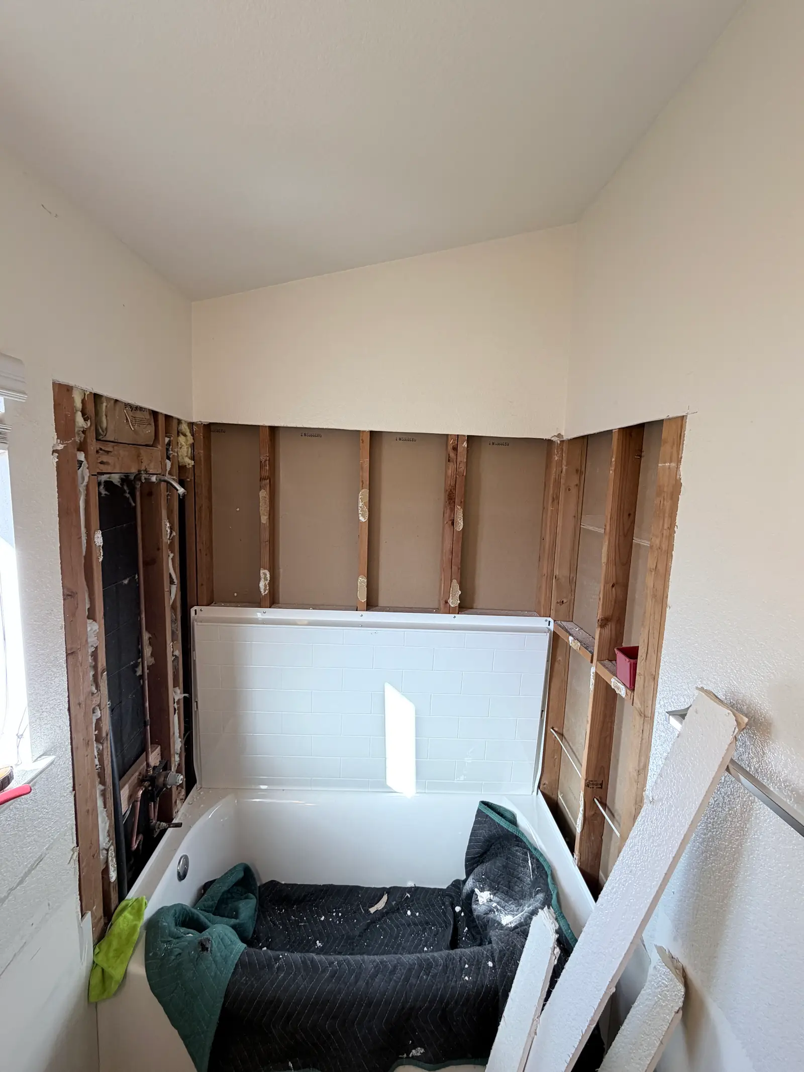 Bathroom wall opened behind tub area during Temecula water damage restoration project by PL Builders