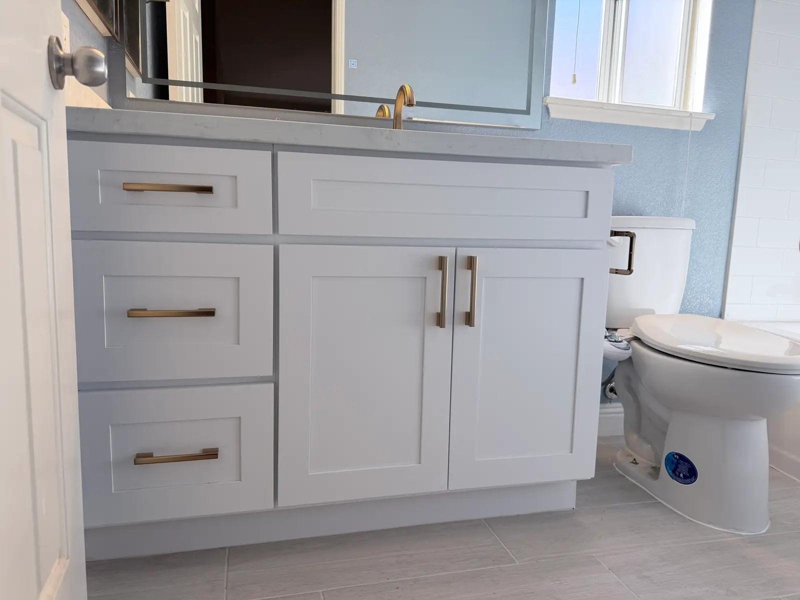 Finished bathroom cabinet and floor detail during Temecula water damage restoration project by PL Builders
