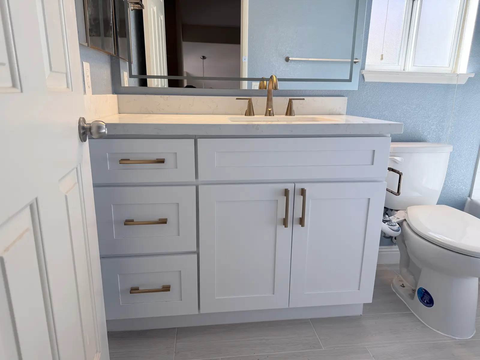 Finished bathroom vanity and toilet area during Temecula water damage restoration project by PL Builders
