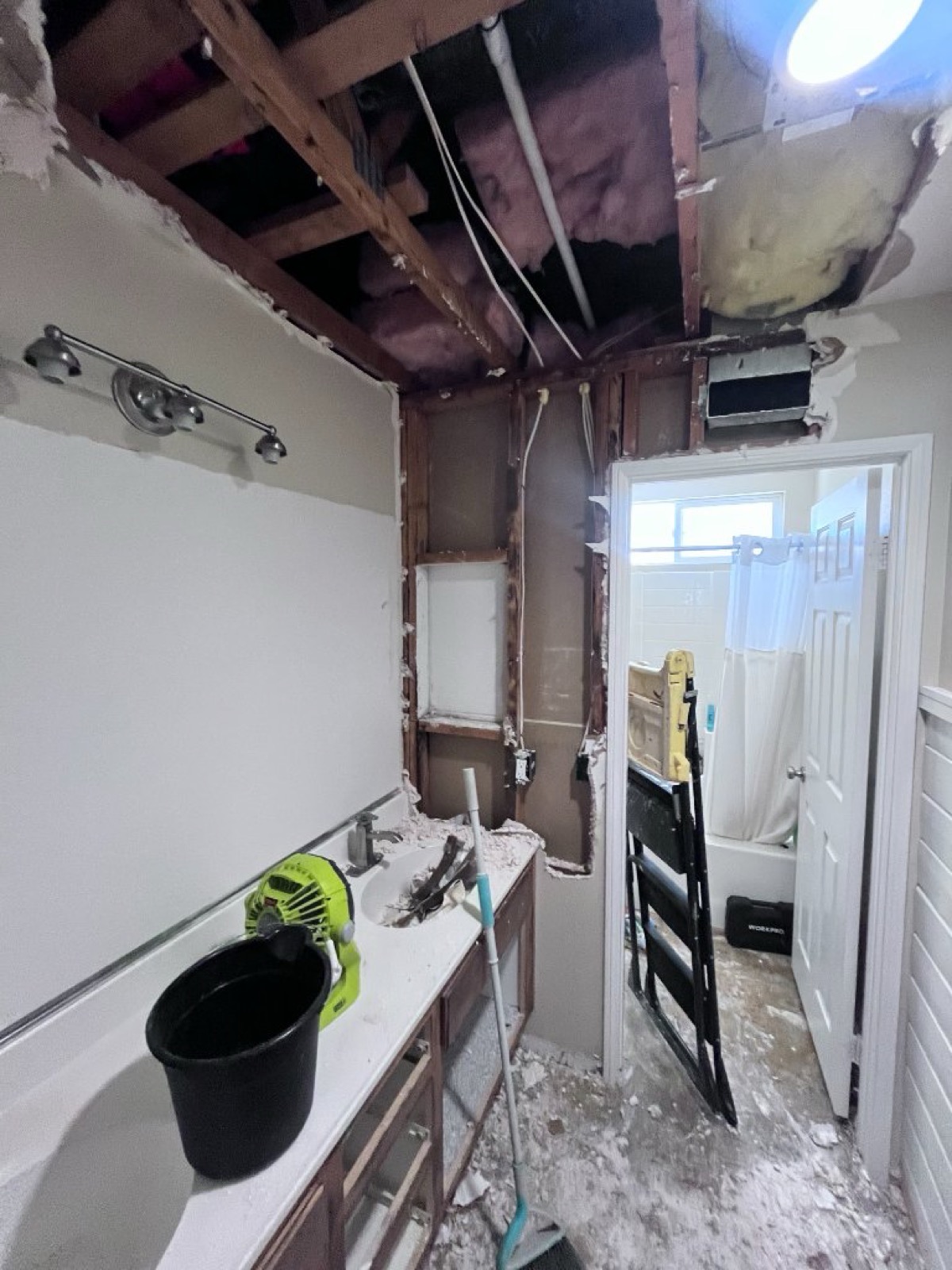 Before: Beautifully restored bathroom with white double vanity, quartz countertop, and wood-look tile flooring after water damage restoration in Murrieta